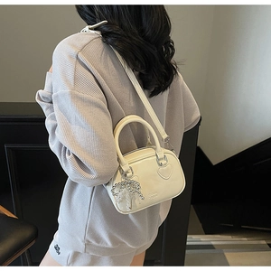 Detailed view of off-white glossy crossbody bag with heart patch and chic beaded charm