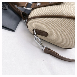 Close-up of woven canvas texture with brown leather trim and silver metal hook detail