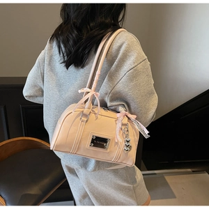 Pink Boston bag detail featuring bow ribbon and heart charm on a grey sweatshirt