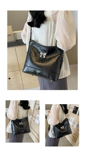 Detail of black tote bag with silver metal bow and textured faux leather finish