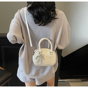 Chic cream leather handbag with heart detail and silver bow charm shown on model