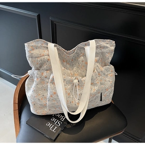 Close-up of floral tote bag with white lace overlay and orange flower patterns