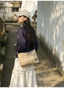 Outdoor shot of khaki nylon crossbody bag styled with casual outfit showing large capacity
