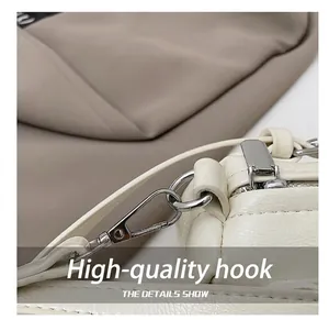 Dettaglio del gancio in metallo lucido e della trama in pelle beige di questa borsa