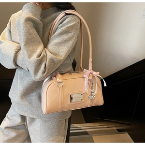 Detail of light pink Boston bag featuring a checkered bow and heart charm on the handle