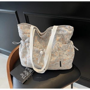 Detail of floral tote bag featuring white lace exterior and woven handles on a vintage chair