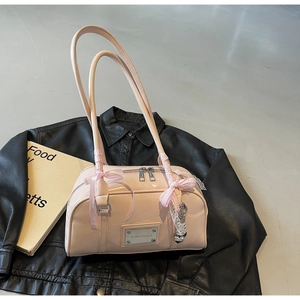 Detailed shot of pink patent leather shoulder bag with bow decor and heart zipper pull