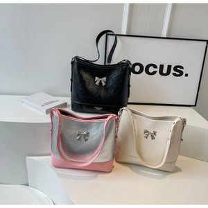 Detail view of stylish bow shoulder bags in black, beige and pink metallic finish