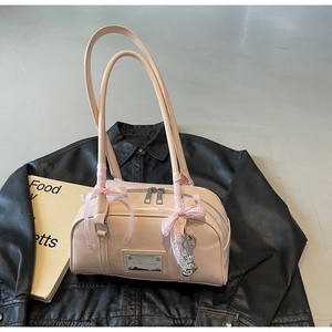 Detail of light pink patent leather handbag featuring ribbon bow and metal ball charm