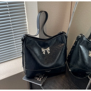 Detail view of the black pleated underarm bag with a silver metal bow accent
