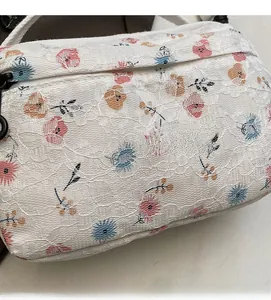 Macro detail of floral lace fabric on a crossbody bag with colorful flower patterns