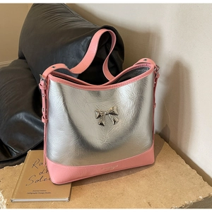 Macro detail of metallic silver shoulder bag with pink leather trim and bow buckle