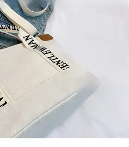 Detail of white canvas tote bag with black and white GENTLEWOMAN printed strap