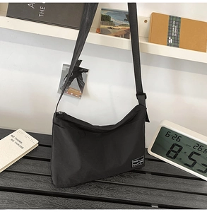 Detailed close-up of waterproof black nylon messenger bag texture and woven brand label