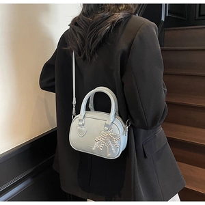Detail of light blue leather mini handbag featuring a pearl bow and heart side patch