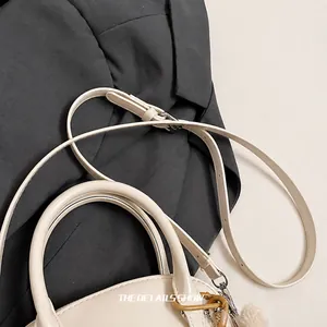 Detalle de bolso de cuero beige que muestra la correa de hombro ajustable y hebilla plata
