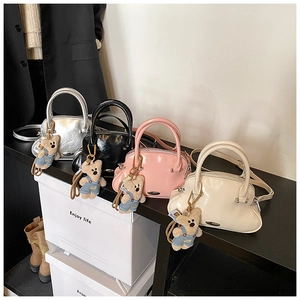 Bolsos de mano brillantes en forma de concha en plata, rosa y negro con dijes de oso