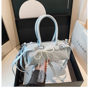 Dettaglio borsa Boston azzurra con fiocco di pizzo e perle e cerniera in metallo argento