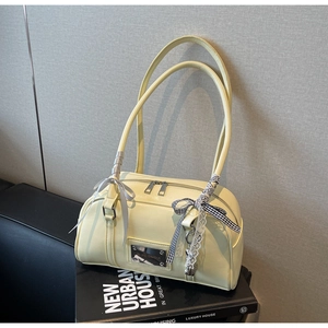 Detail of a creamy yellow Boston shoulder bag with chic ribbon bows and metal plaque