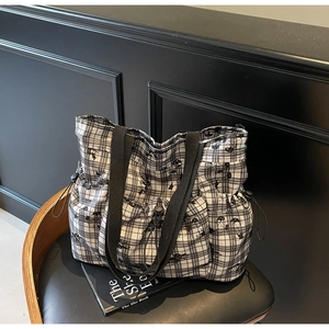 Detail of checkered canvas tote bag with side drawstring pockets on a vintage chair