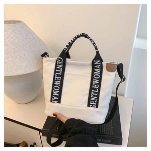 Detail of GENTLEWOMAN canvas tote bag featuring black branded straps and brown leather tag