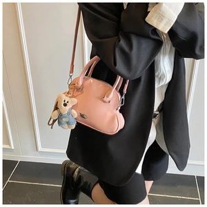 Bolso de charol rosa con colgante de oso mostrado como un elegante bolso bandolera