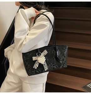 Détail du sac cabas noir embossé avec un nœud en dentelle et un cœur en perles