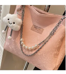 Detail of pink snakeskin tote bag featuring pearl chain and cloud plush charm detail