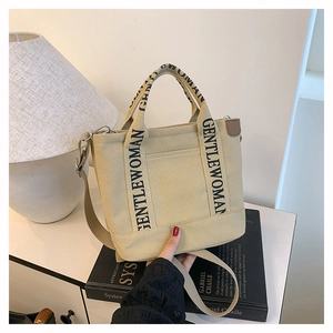 Detail of adjustable strap and black GENTLEWOMAN print on beige canvas tote bag
