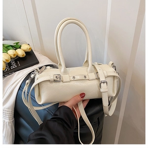 Dettaglio della borsa a baguette cilindrica color crema con trama in pelle e fibbie metalliche