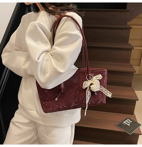 Détail du sac cabas bordeaux à motif serpent avec pendentif en perles et dentelle