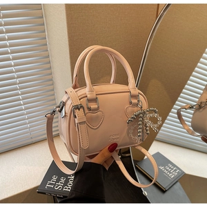 Detail of a dusty pink Boston bag with a bow charm and elegant mirror reflection