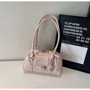 Detail of light pink patent leather handbag with satin bow and heart pendant