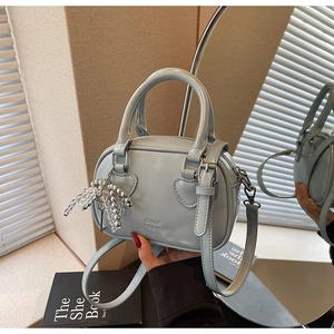 Detail of light blue mini bowling bag with heart buckles and mirror reflection