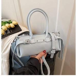 Dettaglio borsa a cilindro azzurra con cinturini in pelle e fibbie metalliche eleganti