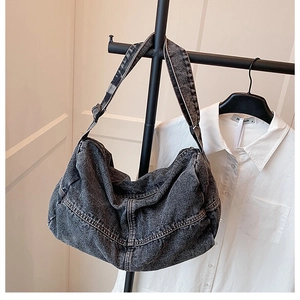 Detail of washed grey denim hobo bag with wide shoulder strap and reinforced stitching
