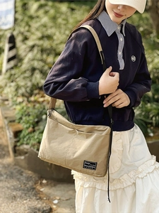 Fashionable khaki canvas tote bag with front pockets and adjustable strap for casual use