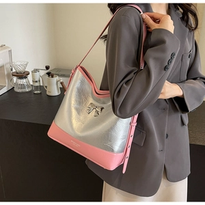 Detail showing pink leather shoulder bag with silver metallic bow and textured fabric