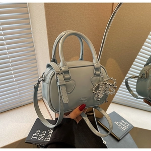 Close-up of light blue leather mini barrel bag with heart stitching and silver bow charm
