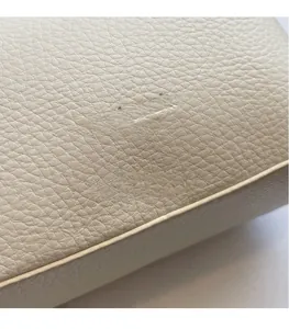 Close-up of cream pebble grain leather with an embossed logo and fine stitching detail