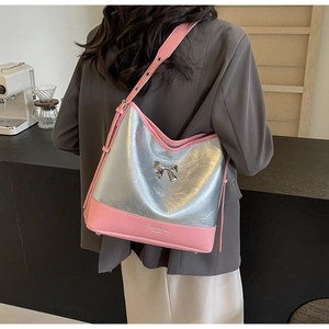 Detail of silver metallic tote with pink leather straps and metal bow accent