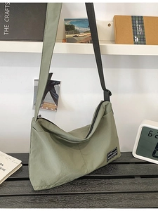 Minimalist green nylon tote bag with adjustable black shoulder strap and zipper closure