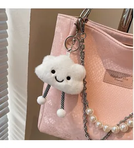 Close-up of a white plush cloud charm with striped legs on a pink handbag