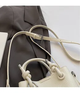 Detail of adjustable shoulder strap and knotted handle on beige lychee leather bucket bag