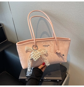 Détail du sac cabas rose effet serpent avec breloque cœur perle et nœud en dentelle