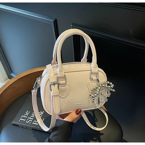 Detail of light pink Boston bag with heart-shaped handle base and silver bead charm