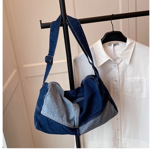Detail of blue patchwork washed denim crossbody bag hanging on a black clothes hanger