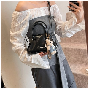 Bolso de mano negro brillante con asas redondas y un bonito colgante de oso de peluche