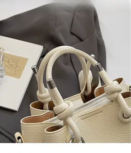 Detail of cream white lychee texture bucket bag with unique knot handle and silver hardware