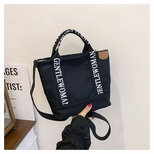 Detail of black canvas tote bag with Gentlewoman logo straps and leather patch